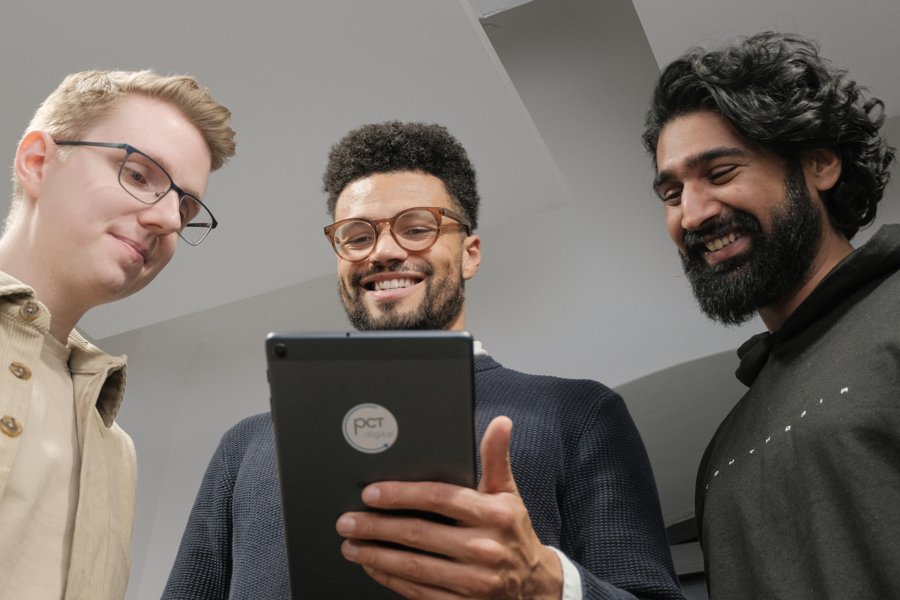 Drei Mitarbeitende schauen gemeinsam auf ein Tablet